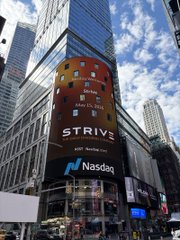 A tall digital billboard in a city (likely Times Square) advertising 'STRIVE' with a Nasdaq listing badge against a cloudy sky backdrop.