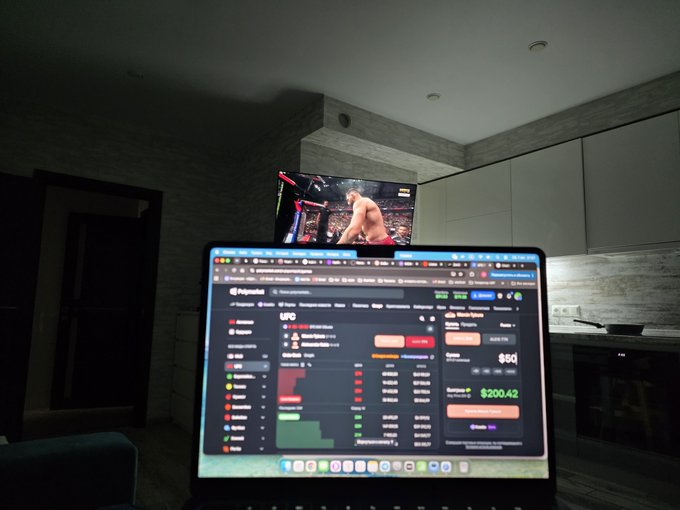 A laptop screen displaying a Polymarket trading interface with UFC odds is shown in front of a television playing what appears to be a UFC fight in a dimly lit living room.