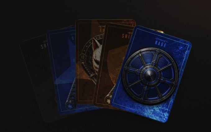 A fan of playing cards spread out on a dark surface, with the rightmost blue card featuring a metallic shield design labeled "STARKNET RACE" and "SHIELD" visible on the others, visually representing the Starknet Shield Rush questing challenge mentioned in the post.