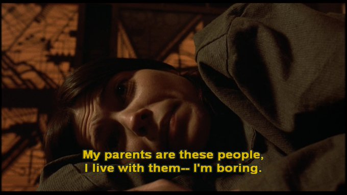 A close-up movie still shows a worried-looking woman lying down with the yellow subtitle 'My parents are these people, I live with them-- I'm boring.'