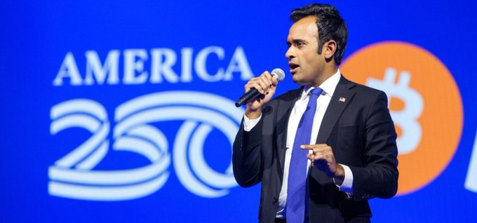 Vivek Ramaswamy speaks into a microphone at the America 250 stage, with a Bitcoin logo visible in the background. The image relates to his company Strive's recent purchase of 79 BTC for $5 million, bringing total reserves to 20,246 BTC.