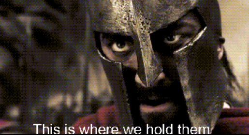 A close-up of King Leonidas from the movie 300 wearing his iconic helmet, with the caption "This is where we hold them" — humorously symbolizing the post's message about steadfastly holding category-leading altcoins through market volatility.