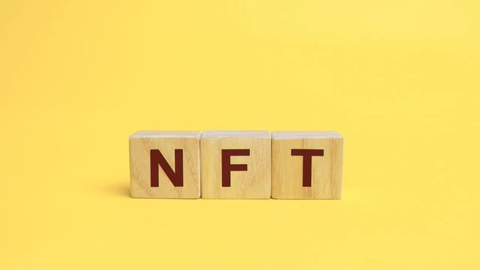 Three wooden blocks spelling 'NFT' against a bright yellow background.