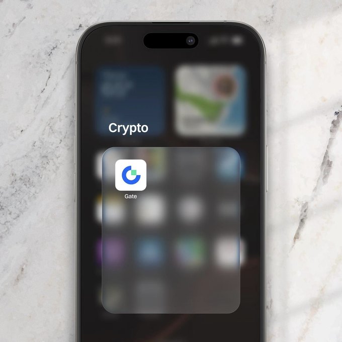 A close-up of a smartphone screen displays the "Gate" cryptocurrency app icon within a folder labeled "Crypto," set against a marble background. The image visually reinforces the tagline "The market moves. Gate moves with you." by highlighting easy mobile access to the Gate trading platform.