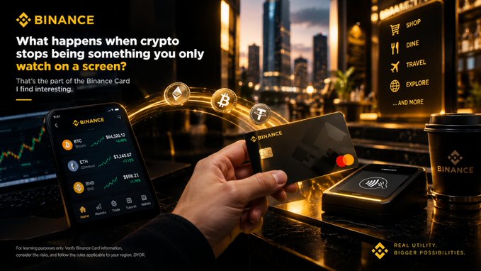 A Binance advertisement showing a hand holding a Binance Card next to a smartphone displaying cryptocurrency prices, with the tagline 'What happens when crypto stops being something you only watch on a screen?'.