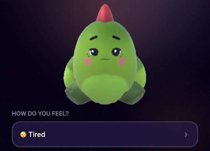 A cute green dinosaur-like character from the Sleepagotchi app appears with a sleepy expression above a "HOW DO YOU FEEL?" prompt showing the option "Tired" with a yawning emoji, reflecting the user's morning update about waking up and checking their sleep insights, which have made tracking their improving sleep patterns engaging and fun through gamification with the $SLEEP token.