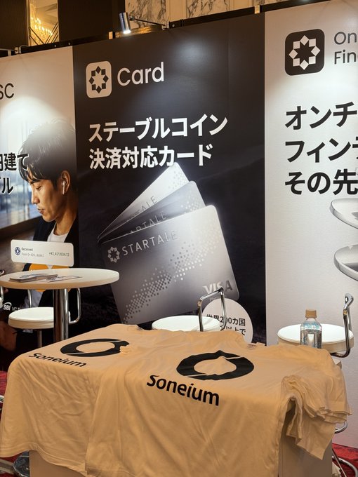 A Soneium exhibition booth in Tokyo features branded merchandise and signage promoting "Startale" stablecoin settlement cards and on-chain finance, ahead of the WebX Asia event held July 13–14 at The Prince Park Tower. A staff member stands at the booth alongside a laptop, ready to engage with attendees about the Soneium ecosystem.