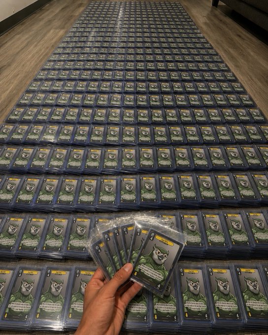 A hand holds up a fan of "Gigabirb" trading cards while thousands of identical cards are spread across the floor, demonstrating the poster's massive stockpile of the rare card from @vibes_tcg to humorously illustrate their quest to own the market majority on this single character.