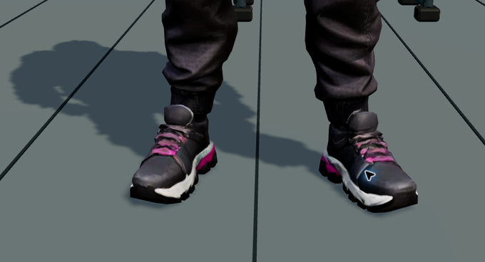 A close-up view of a person's legs and feet wearing black pants and black, white, and pink high-top athletic sneakers standing on a gray floor.