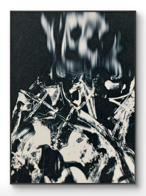 A black and white abstract artwork or photograph with dramatic lighting, showing jagged metallic-looking shapes and blurred flames.