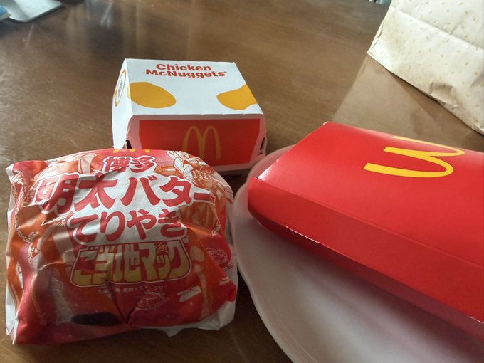 The image features a dining table with three McDonald's food items placed on it, including two boxes of chicken nuggets and a box of chicken tenders. The background appears to be a wooden surface or countertop. The text "おはようございます今日は検査があるので今朝はランオフ、また梅雨空に逆戻り、走りもとってもしくないようにしておく" is present, which seems to be a reference to the post about McDonald's chicken nuggets.