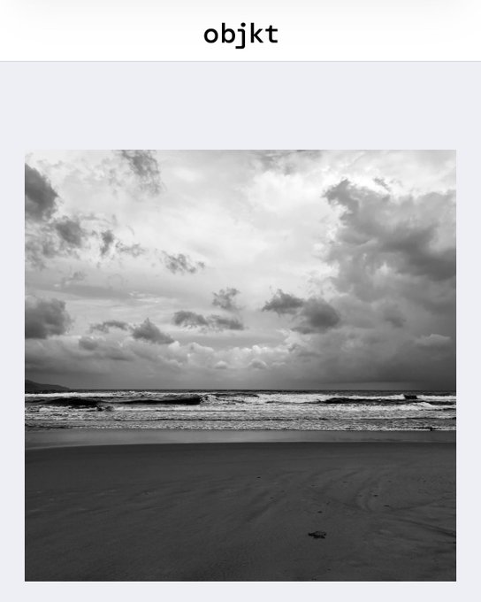 A black-and-white photograph of a cloudy sky over a beach with waves, titled 'objkt' at the top.