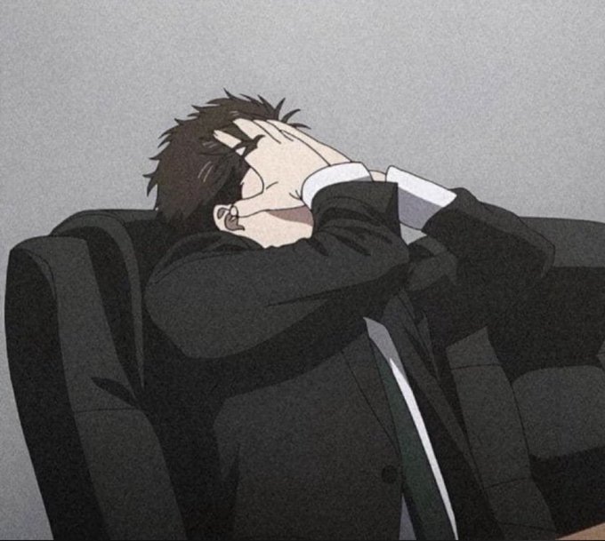 An anime-style drawing of a young man in a dark suit sitting on a gray couch, leaning back with his hands covering his face in a gesture of exhaustion or frustration.