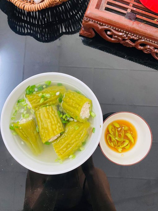 The image features a bowl of food with green vegetables, such as corn or zucchini, sitting next to a small cup filled with sauce. The bowl appears to be placed on top of a table, while the cup is positioned below it. The background of the image shows a blurred view of a dining table and chairs. The post includes text that reads "GM X Wishing everyone a productive day, good vibes, and meaningful connections @TheARCTERMINAL | @useTria | @RiverdotInc | @NucleusCodes | @quipnetwork | @sleepagotchi".