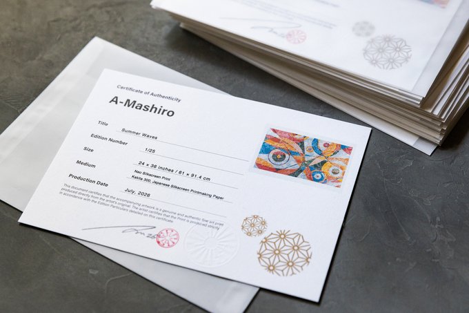 A Certificate of Authenticity for an artwork titled 'Summer Waves' by artist A-Mashiro, edition 1/25, medium size (24 x 36 inches), printed on Hahnemühle Photo Rag Baryta paper, dated July 2026. The certificate sits atop a stack of similar print sleeves on a gray surface.
