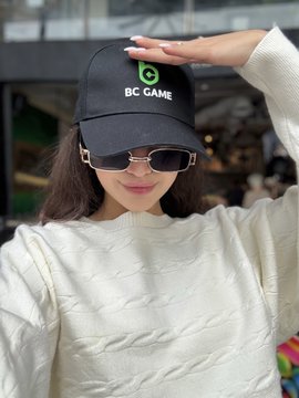 A woman wearing a black cap with "BC GAME" logo and sunglasses contributes to the celebratory post about $BC hitting an all-time high again. The image connects to the post by showcasing the BC Game brand, reinforcing the bullish sentiment on the $BC token.
