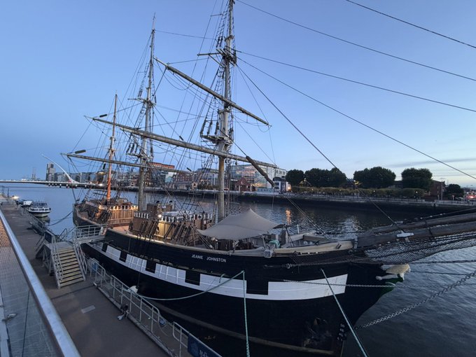 A historic tall ship named "JANE JOHNSTON" is docked at a harbor, its tall masts and rigging silhouetted against the evening sky, embodying the classic "Seaship" as opposed to the "Starship" referenced in the post. The vessel's weathered hull and traditional maritime design evoke a bygone era of seafaring.