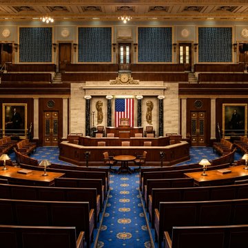 The image shows the empty chamber of the U.S. House of Representatives, with rows of desks facing the Speaker's rostrum where the American flag is displayed.

The image depicts the U.S. House of Representatives chamber, providing a visual of the congressional setting where the CLARITY Act counteroffer would be debated by lawmakers.