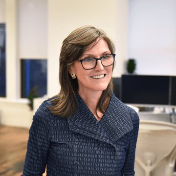 A woman with shoulder-length brown hair wearing glasses and a textured navy blue jacket smiles at the camera in what appears to be a modern office setting, likely Cathie Wood given the context of ARK Venture Fund news.

Based on the accompanying post, this appears to be Cathie Wood, CEO of ARK Invest, pictured as her firm announces tokenizing its ARK Venture Fund (ARKVX) on Ethereum through Securitize—the fund notably holding stakes in OpenAI and Anthropic.