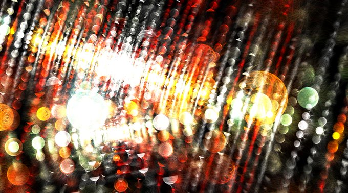 An abstract, out-of-focus photograph featuring vibrant bokeh lights in red, orange, white, and green with streaks of light.