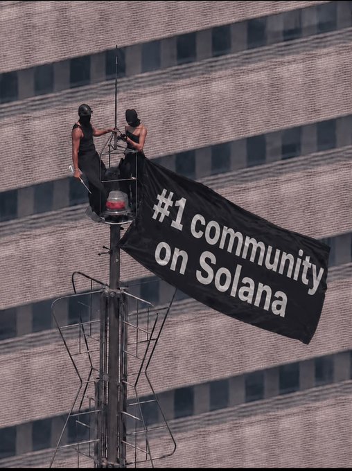 Two people scale a communications tower to unfurl a large black banner reading "#1 community on Solana," with the post referencing "Solflare Empire" suggesting a promotional stunt celebrating Solflare's ranking within the Solana ecosystem.