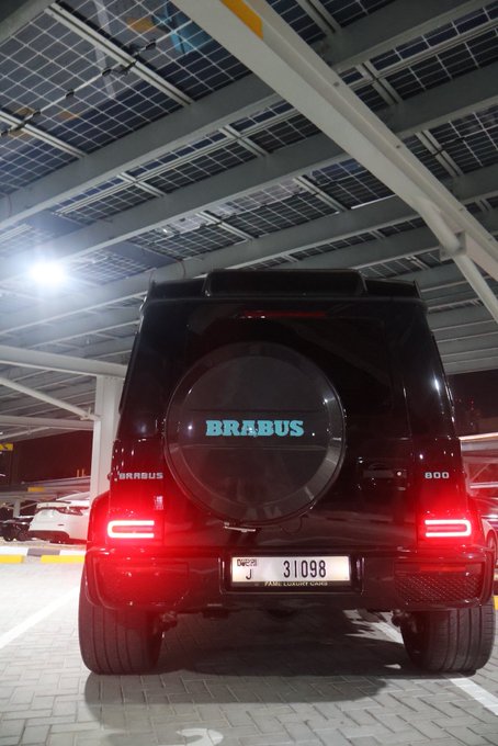A black Brabus 800 SUV is parked in a parking garage, with its rear spare tire cover displaying the "BRABUS" logo and "800" badge, along with an Abu Dhabi license plate reading "31098 J". The "GN" caption likely refers to the car owner's initials, fitting Brabus's reputation for custom-tuned luxury vehicles often personalized for elite clients.