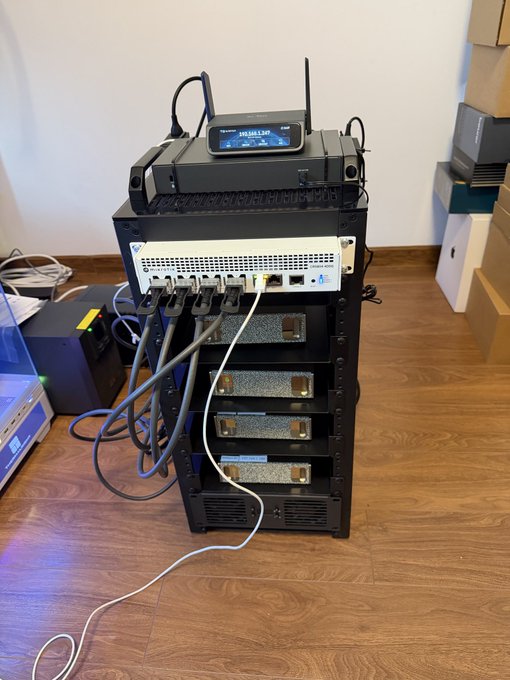 A cryptocurrency mining setup featuring a miner device stacked on a rack with power supplies and connected cables on a wooden floor.
