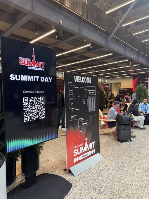 A summit event signage displays 'SUMMIT DAY' with a QR code for the detailed agenda, alongside a 'WELCOME' banner with a venue map for 'SOLAR SUMMIT CHICAGO 2025' in an open lobby with seating.