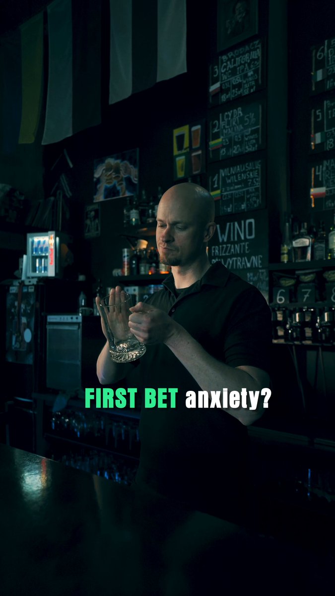 The image features a man standing at a bar, holding a glass of wine or beer. The text "First Bet Anxiety?" appears below him, suggesting that he might be feeling anxious about making his first bet on a sports event.