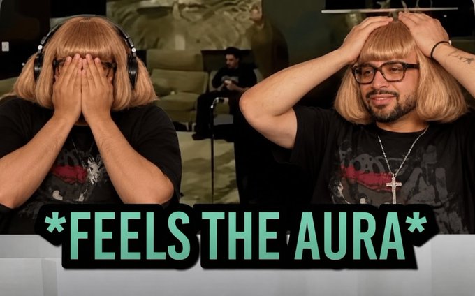 Two men wearing matching blonde bob wigs react emotionally, with one covering his face and the other grabbing his hair, captioned '*FEELS THE AURA*'.