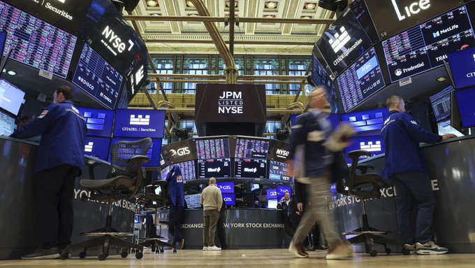 The trading floor of the New York Stock Exchange with visible signs for 'NYSE', 'JPM', 'GTS', 'Lice', 'Goldman Sachs', 'CITADEL Securities', and 'ProShares'.