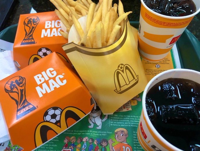 McDonald's meal on a tray featuring two Big Mac FIFA World Cup-branded boxes, french fries, and two soft drinks on a paper liner with Portuguese text about the 2026 World Cup.