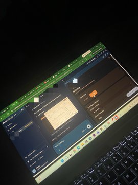 A laptop screen displays what appears to be a spreadsheet application in a dark room, showing a table with data entries.