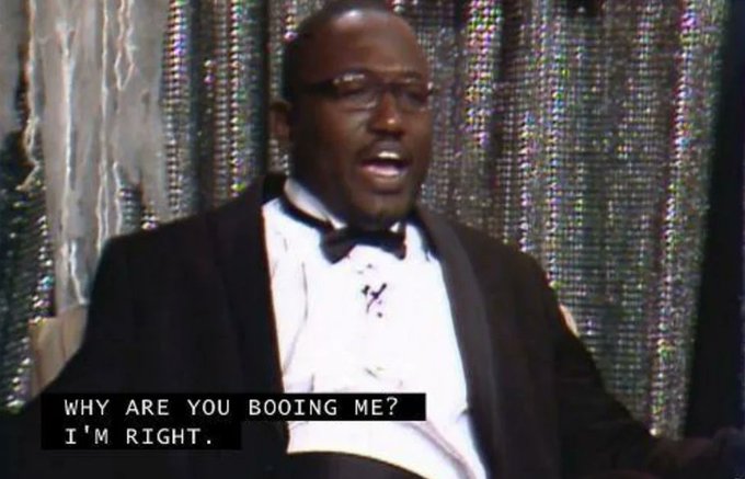 A man in a tuxedo sings or speaks on a glittery stage, with subtitles reading, “WHY ARE YOU BOOING ME? I’M RIGHT.” The meme-style image accompanies the post “Flood,” likely using the performer’s emphatic reaction to convey frustration or protest.