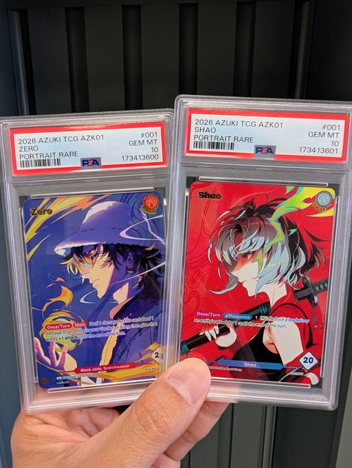 A hand holds two PSA-graded Azuki TCG cards from 2026 Set AZK01: "Zero" (#001) and "Shae" (#001), both rated Gem Mint 10 and labeled Portrait Rare, showcasing the user's graded grail cards from the collection's first set as they anticipate Set 2.