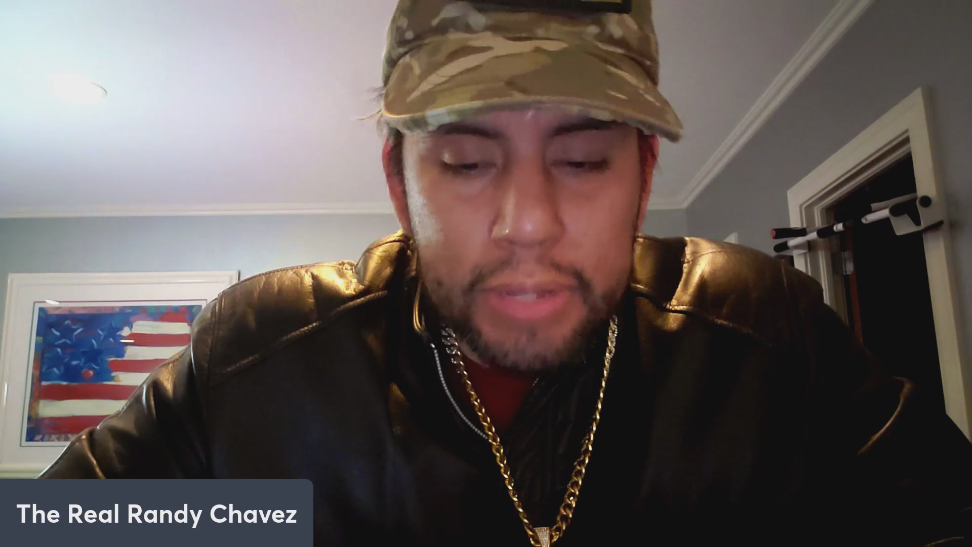 The image features a man wearing a camo hat, black jacket, and gold chain necklace. He has his eyes closed and appears to be looking down at something or someone. The caption of the image reads "VeVe launches Original IP! VeVenaut! $OMI $DEFX Dacat talk!". This suggests that the man might be participating in a virtual event or discussion related to the content displayed on the image, possibly about military life or other topics relevant to the camo hat and black jacket.