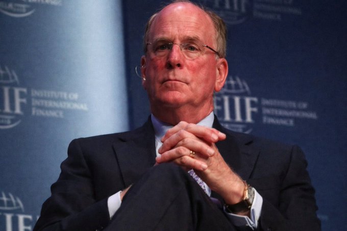 Larry Fink, CEO of BlackRock, sits thoughtfully with hands clasped at an Institute of International Finance (IIF) event, a striking visual irony given BlackRock's recent sale of $54.8 million worth of Bitcoin.