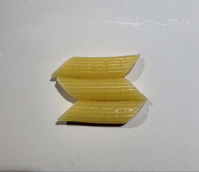 Three glossy, ridged yellow parallelogram strips are stacked on a white surface, forming a rough geometric mark. The image appears to show a physical or mockup interpretation of the proposed new Solana logo, with no visible text or ticker.