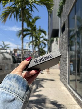 A hand holds up a small Solflare-branded box in front of the Solana-themed building with palm trees in the background, symbolizing the conclusion of the author's tenure at the company. The image captures a personal memento of their time working with the prominent Solana ecosystem brand.