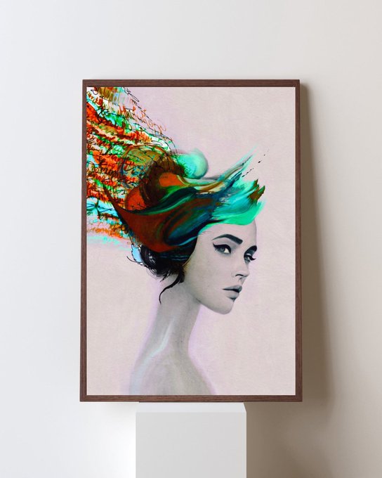 A framed art print on a white pedestal depicts a black-and-white portrait of a woman whose head is exploding into vibrant green, orange, and red splashes of paint.