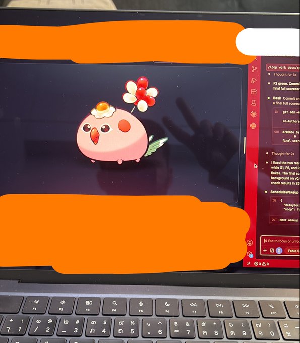 A laptop screen displays a pink 3D character with a fried egg on its head alongside a thought bubble containing red spheres, with chat interface text visible on the right.