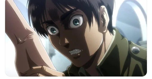 An anime character with dark hair and wide, intense eyes is shown in a close-up shot, appearing shocked or surprised, wearing a green military-style jacket.