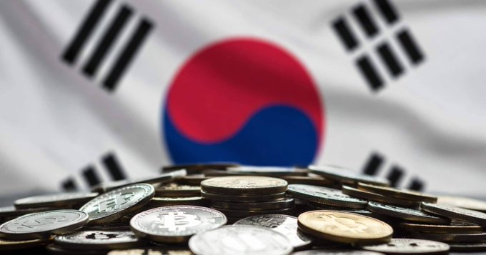 A close-up image shows a pile of Korean won coins with the South Korean flag blurred in the background.