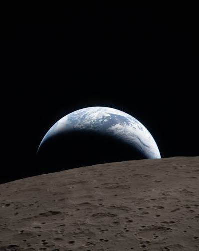 A view of Earth rising over the gray, cratered lunar surface against the black backdrop of space.