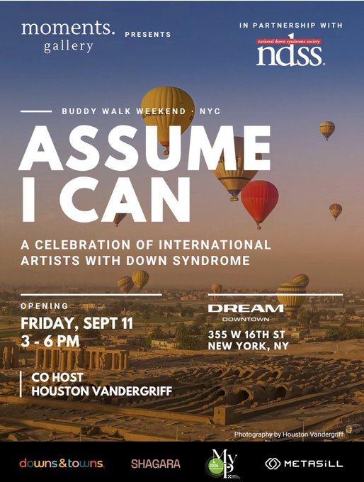 A promotional poster for 'Assume I Can: A Celebration of International Artists with Down Syndrome,' presented by Moments Gallery and NDSS, with an opening on Friday, Sept 11 from 3-6 PM at Dream Downtown (355 W 16th St, New York, NY), co-hosted by Houston Vandergriff, featuring background photography of hot air balloons over a landscape by Houston Vandergriff.
