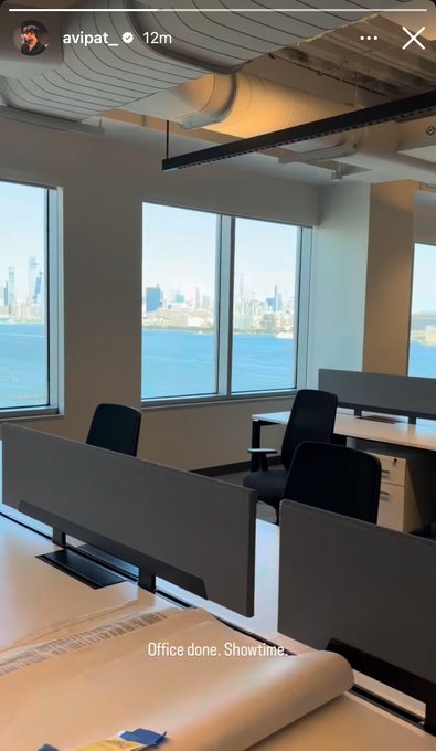 An Instagram story from user 'avipat_' showing an empty office space with desks and chairs facing windows with a city skyline view, captioned 'Office done. Showtime.'