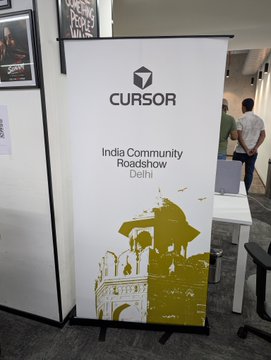 A banner stand displays 'CURSOR' logo and 'India Community Roadshow Delhi' with golden architectural illustrations of Delhi monuments.