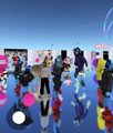 A blurry photo of a crowd of people outdoors at what appears to be a gathering or event, with a white circular sticker visible on the lens.