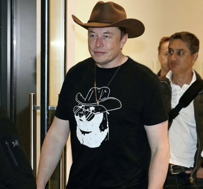 In the image, a man wearing a cowboy hat stands out against the background of another person who appears to be looking at him. They are both standing near a door or an entrance, possibly indicating that they are in a building with multiple levels. The cowboy hat and t-shirt worn by the man suggest he might have a strong connection to western culture or simply enjoys dressing like a cowboy. The post "The Cowboy Driving" seems to be related to this image, as it features a picture of a cowboy driving a car. This could imply that the man in the cowboy hat is associated with the cowboy driving theme and possibly has some involvement in the world of western movies or culture.