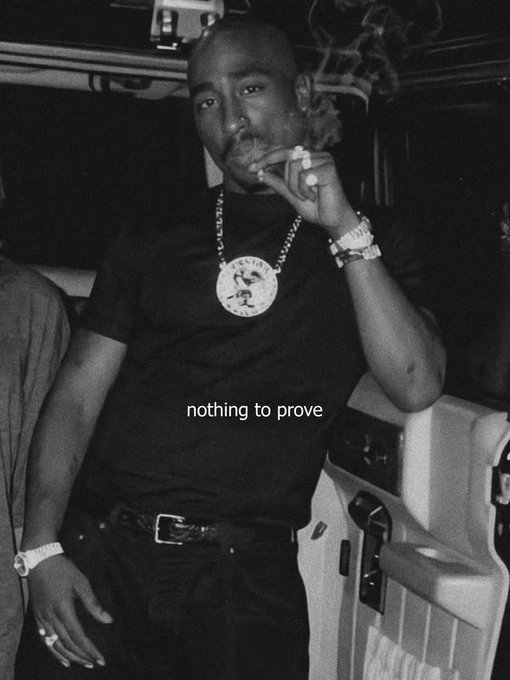 A black-and-white photo of Tupac Shakur smoking, wearing a black t-shirt, large medallion, and rings, with the caption 'nothing to prove' overlaid.